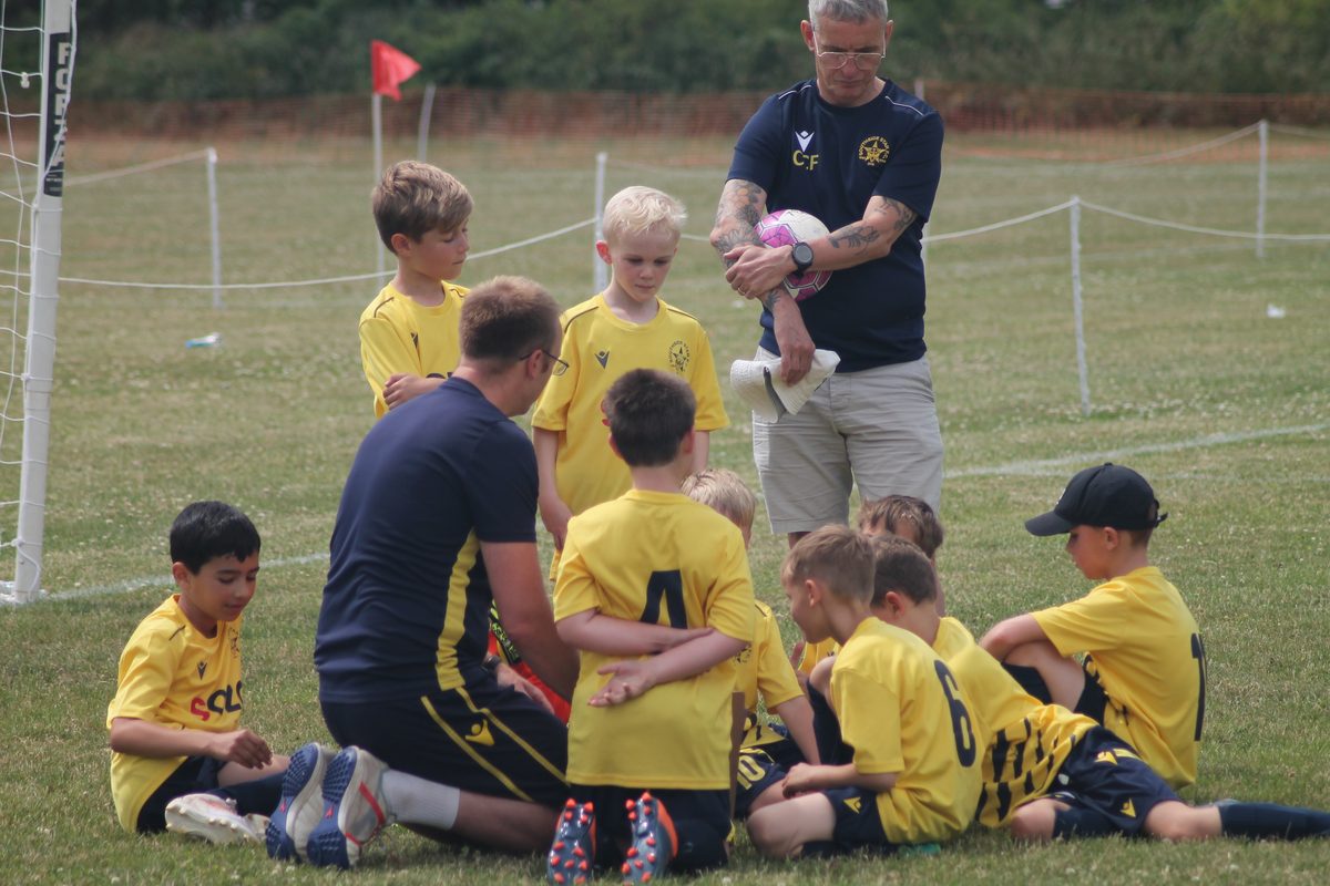 A Southside Star coach giving a team talk to young players sitting on the pitch